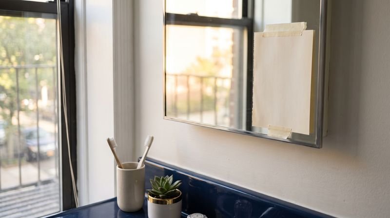A single page taped to a bathroom mirror in morning light